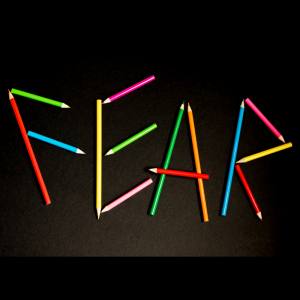 Colored pencils are used to write out the word fear. The sharp angles of the pencils emphasize the danger fear can represent.